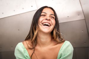 Graduating senior laughs while sitting in front of a metal wall at the MoPop Museum Seattle for her senior shoot.