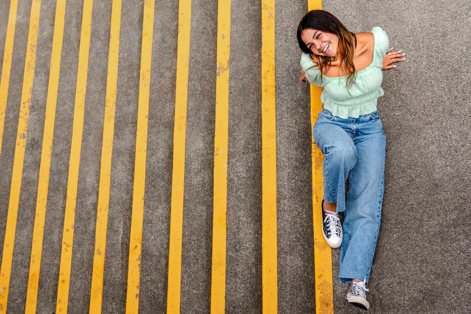Teen girl smiles and poses at the top of staircase with yellow paint for a Senior Session near Seattle Center
