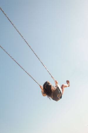 Girl swings up towards the sky at a waterfront playground in Lincoln Park, West Seattle.