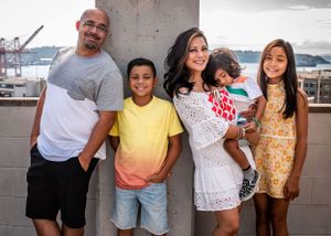 Family of five & the Puget Sound in the background during a family photo shoot on the rooftop of Butler Garage Seattle