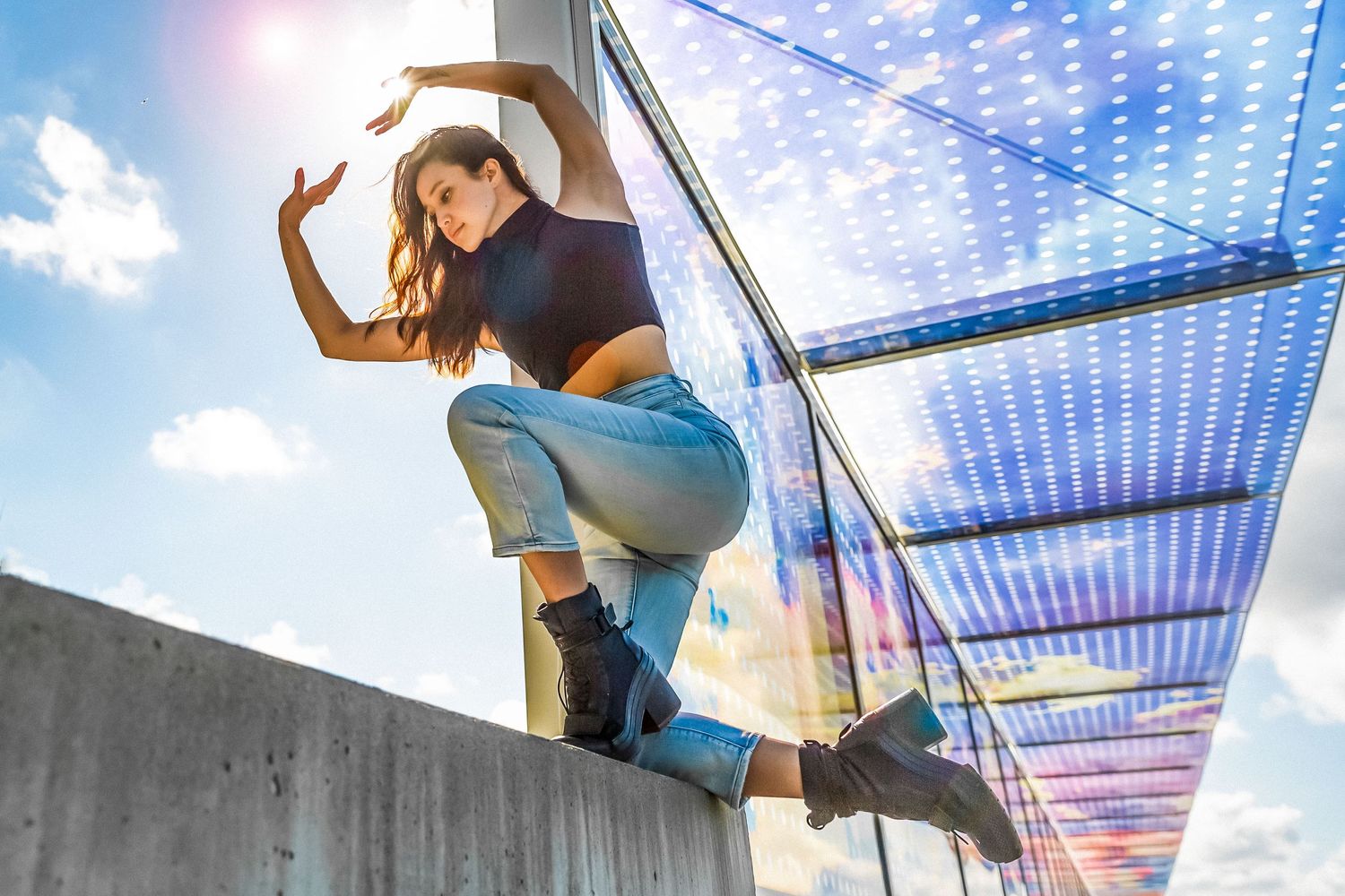 Dancer kneels on a concrete wall at the Olympic Sculpture Park for a dance photo shoot in Seattle, Washington