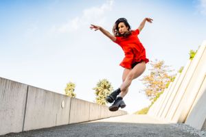 Dancer executes a beautiful jump in a red dress at The Olympic Sculpture Park in Seattle for a dance photo shoot.