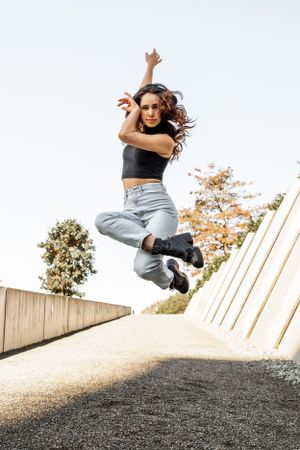 Olympic Sculpture Park: Straight on image of a dancer jumping in a crossed double tuck position wearing jeans.
