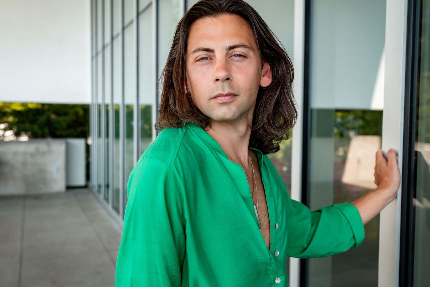 A person wearing a green dress stares in to the camera, standing by mirrored glass at the Olympic Sculpture Park Seattle