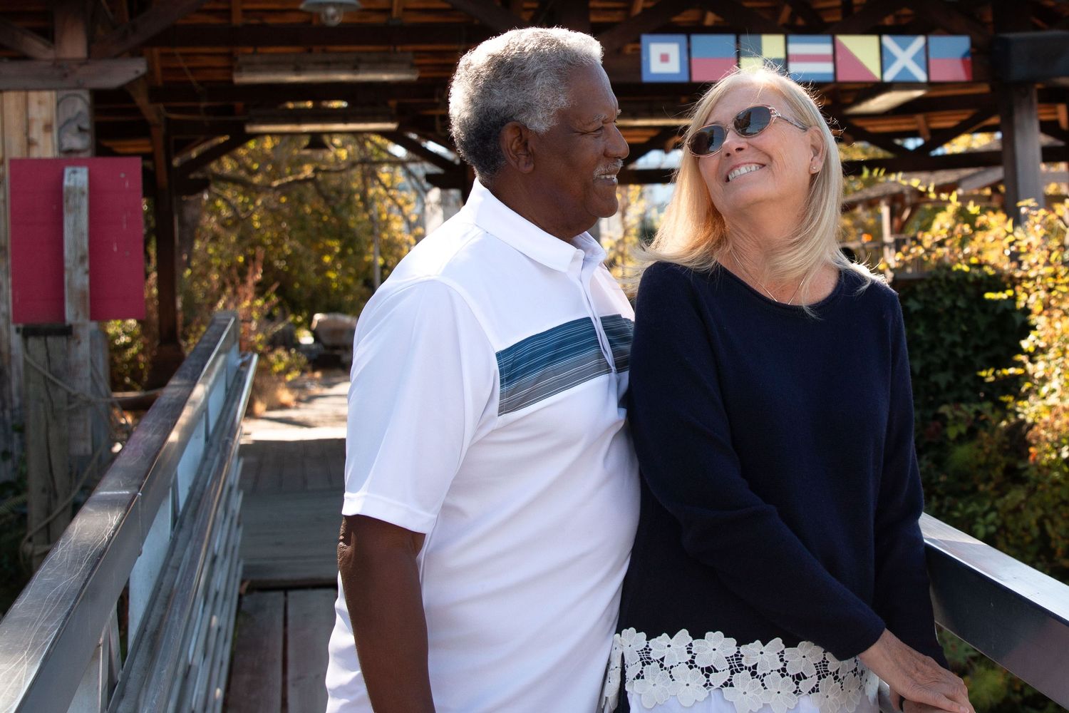 A smiling couple looks at each other while on a bridge near the Center for Wooden Boats in South Lake Union Seattle.