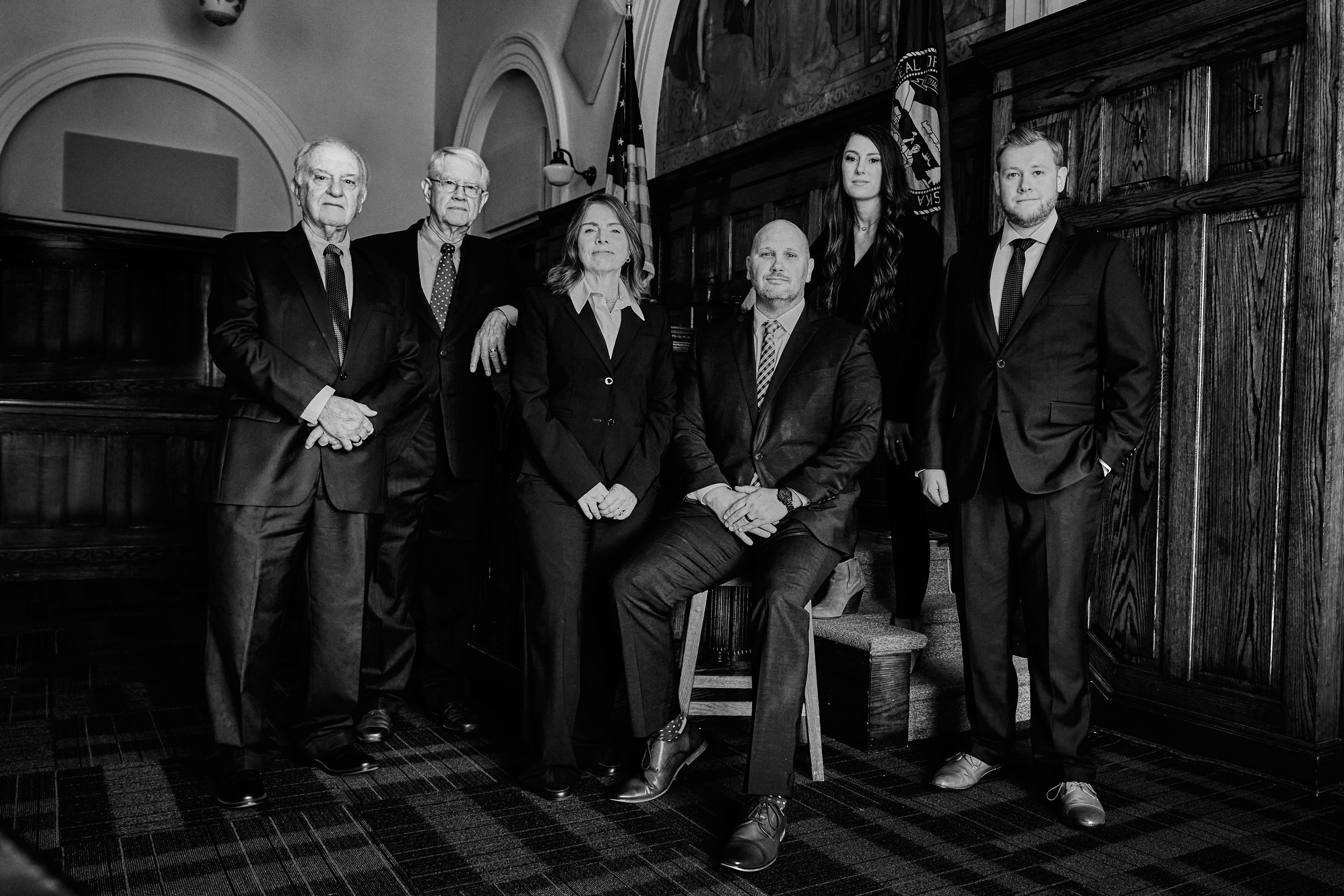 Group portrait in formal attire against dark wooden paneling.