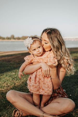 Intimate outdoor photoshoot of parent and baby in complementary outfits during golden hour.