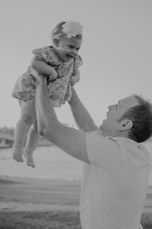 Black and white photos showing playful moments between adult and baby in outdoor setting.