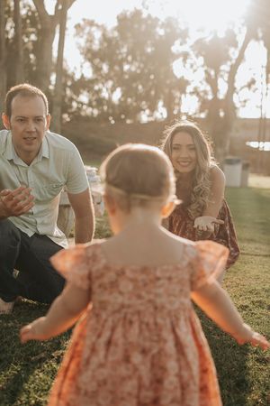 A family shares a joyful moment together on grass during sunset.