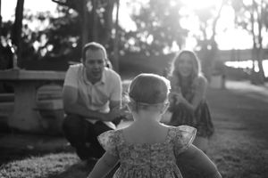 A black and white photo of a family sharing a playful moment outdoors.