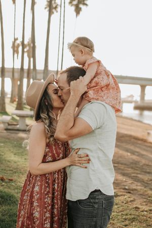 A tender family moment captured at sunset near palm trees.