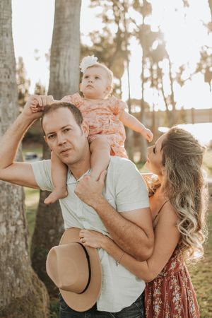 Family plays and laughs together during golden hour photoshoot in a park setting.