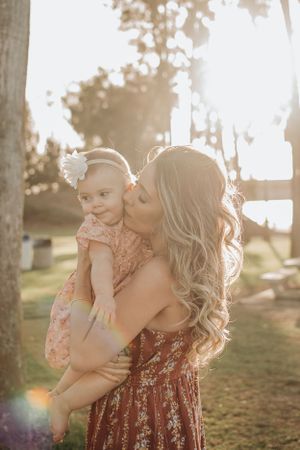 A tender moment between parent and baby in warm golden sunlight outdoors.