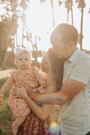 Family shares joyful interactions during outdoor sunset photoshoot.