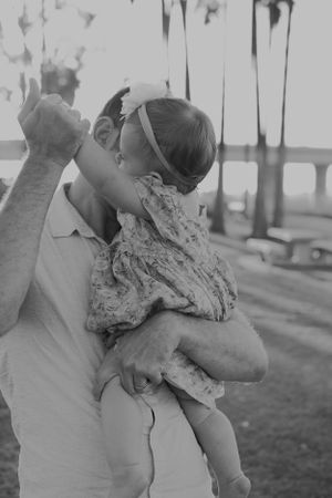 Black and white portrait of parent playing with baby outdoors.