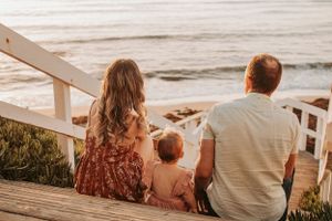 Family sitting together on beach during golden hour sunset.