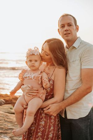 Family sharing tender moments together on rocky beach at sunset.