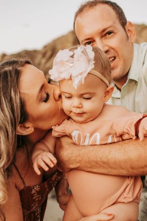 An intimate family moment captured on the beach with warm sunset lighting.