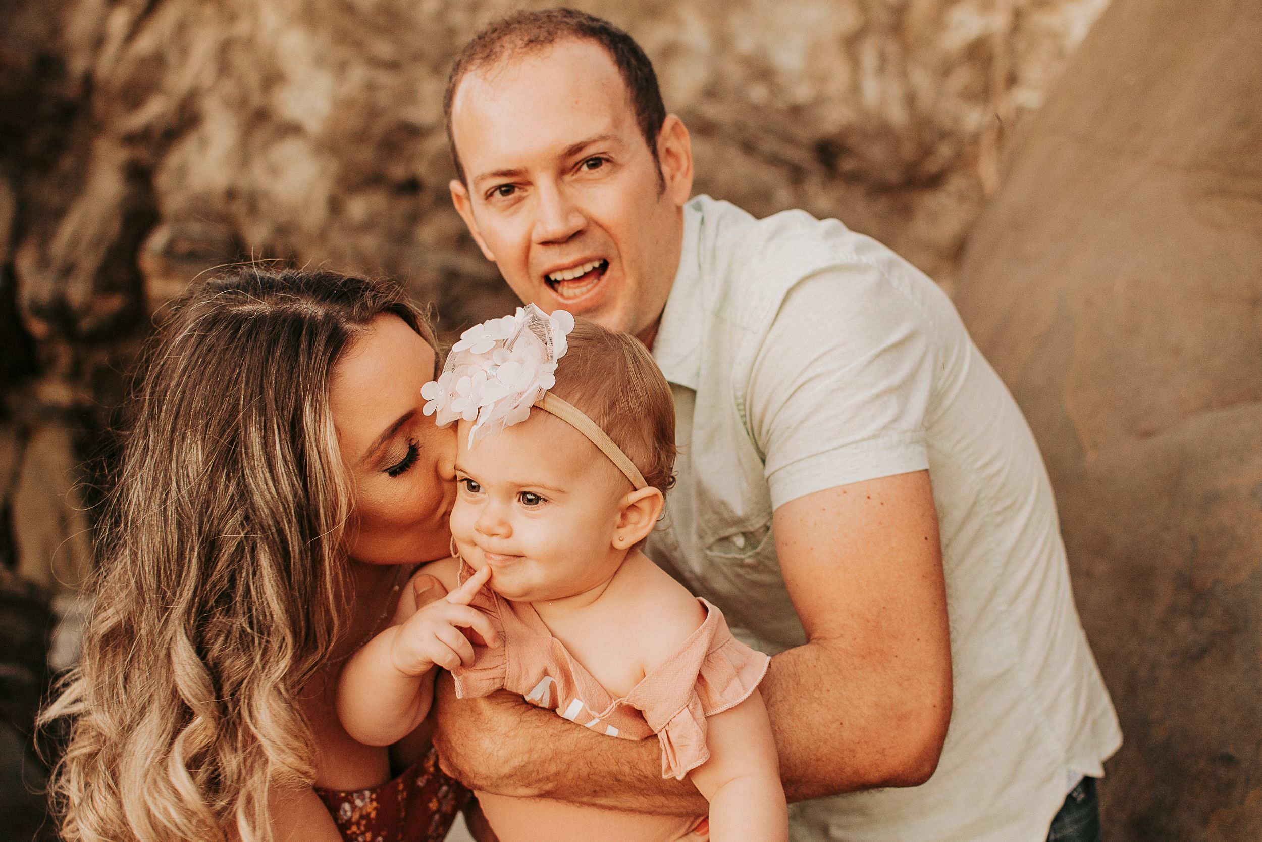 A loving family portrait taken against dramatic coastal rock formations.