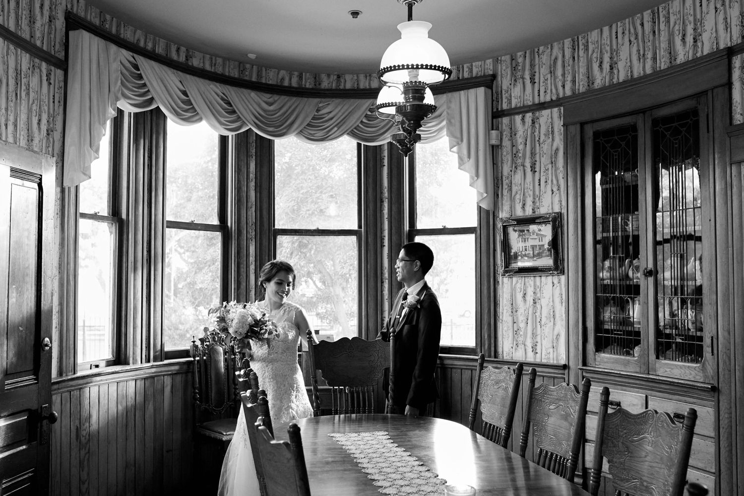 A vintage black and white photo of two people in an elegant Victorian-style room.