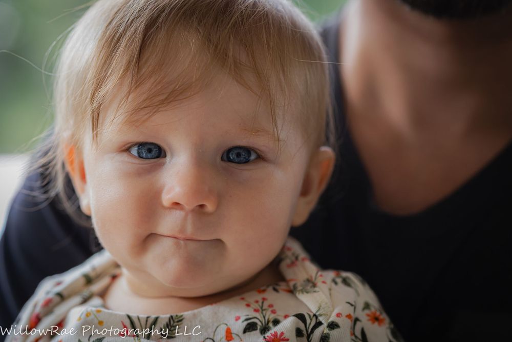 Close-up portrait of baby with blue eyes being held.
