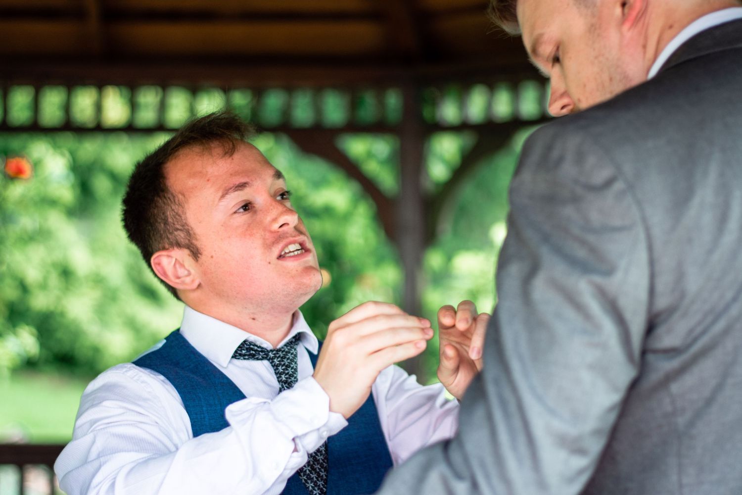 Two wedding guests sharing a lighthearted moment under a pavilion.