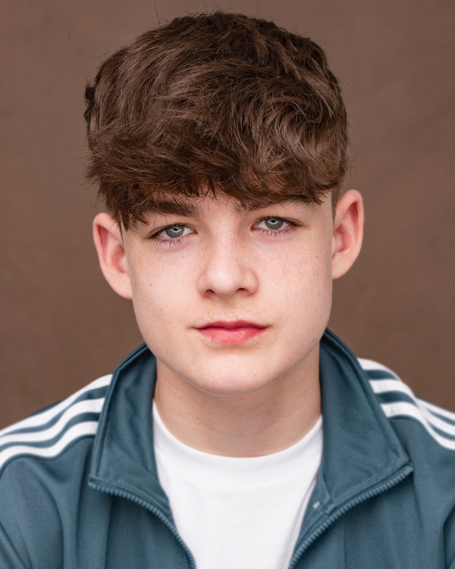 Youth headshot wearing striped athletic jacket against brown background.