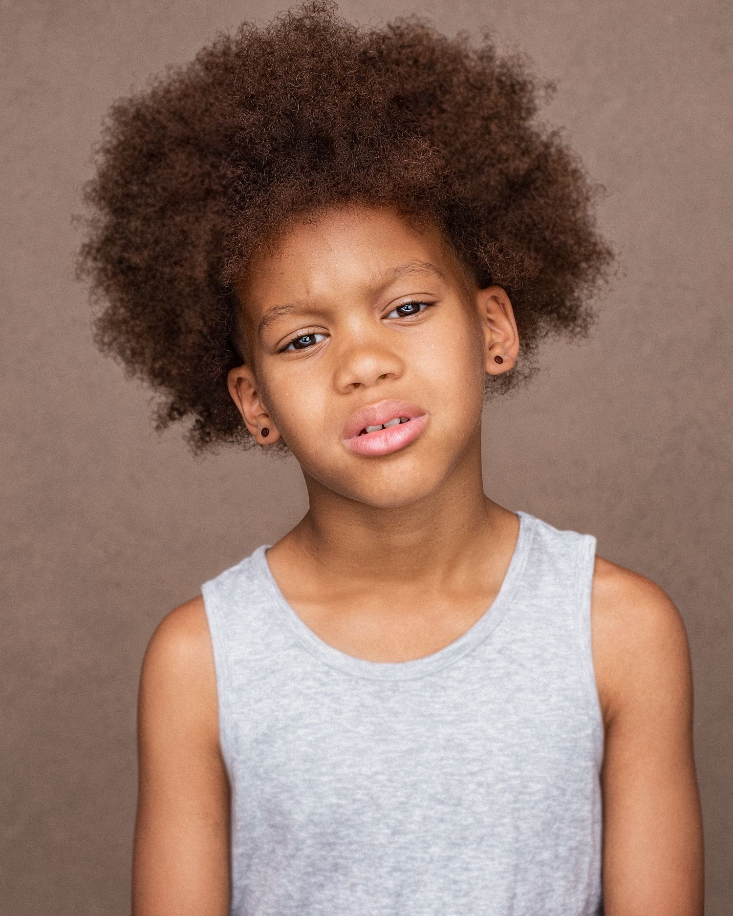 Studio portrait of youth with natural afro hairstyle wearing grey tank top.