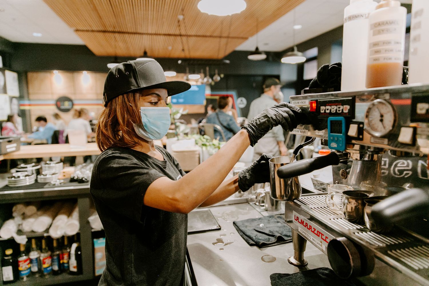 Coffee shop baristas working behind counter with espresso machines.