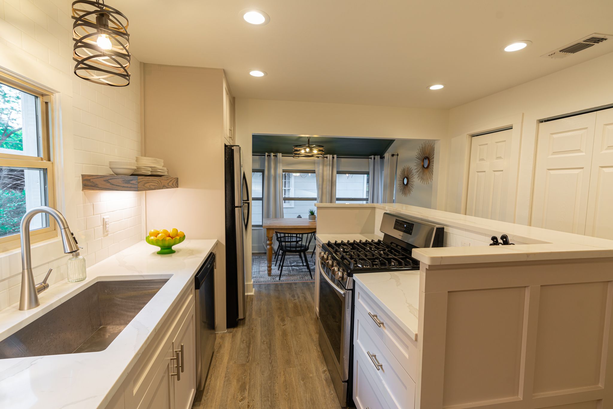 Modern white basement laundry room with recessed lighting, built-in cabinets, and hardwood flooring.