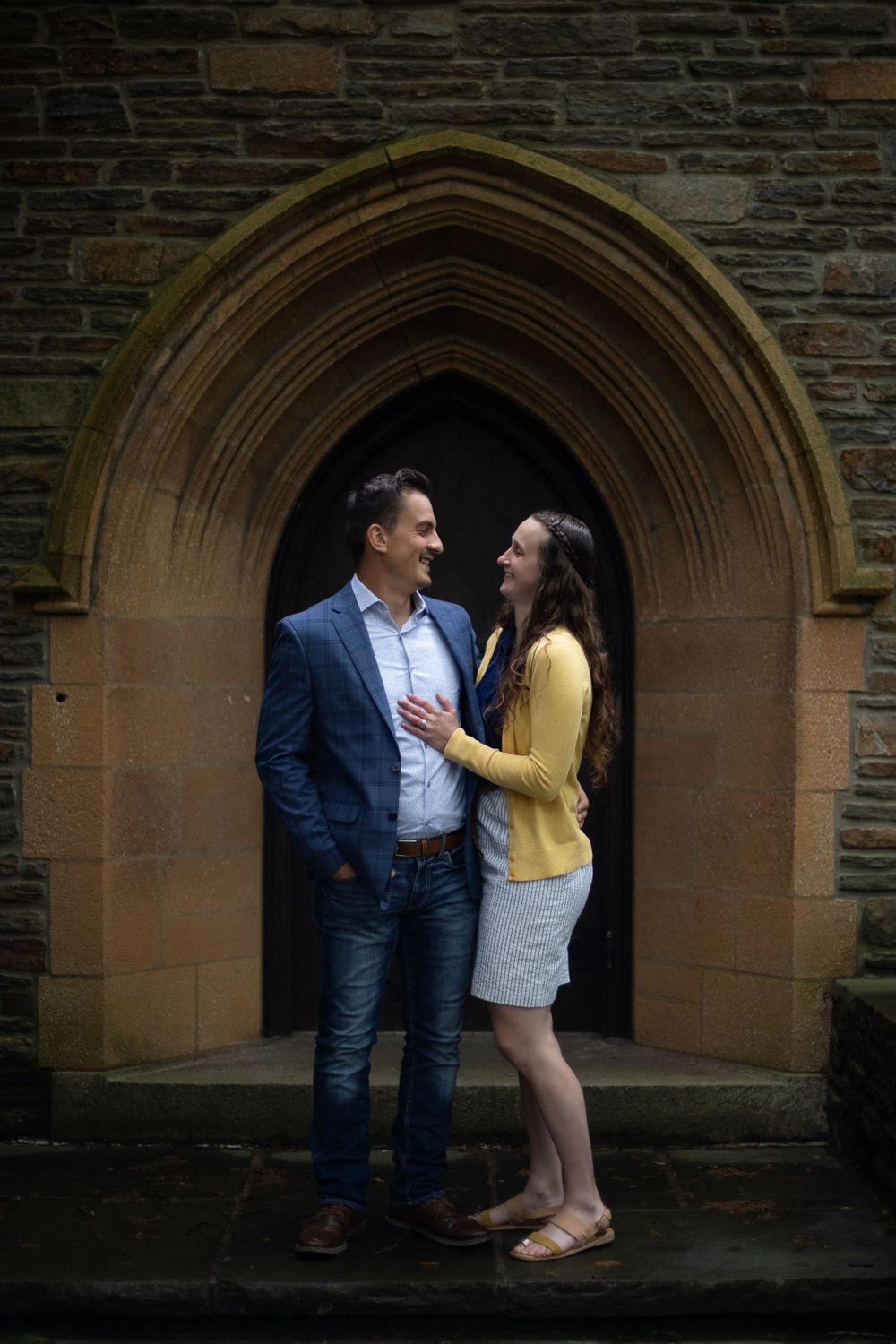 Couple sharing intimate moment under Gothic stone archway.