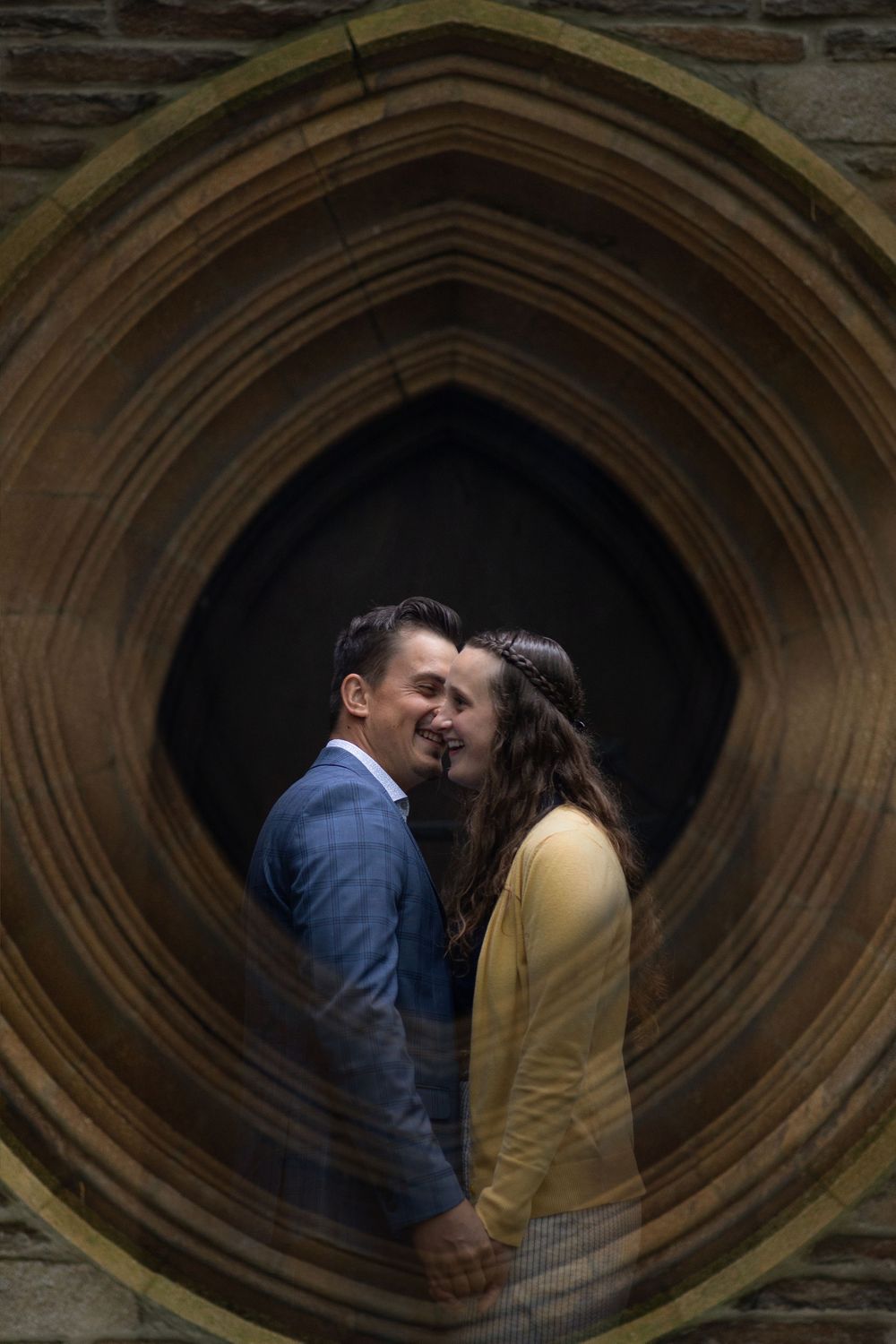 Artistic framed shot of couple through circular Gothic archway.