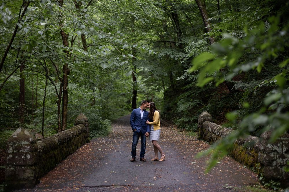 Couple standing together on a stone path surrounded by green forest.