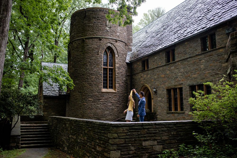 Historic stone tower and building with couple standing in archway entrance.