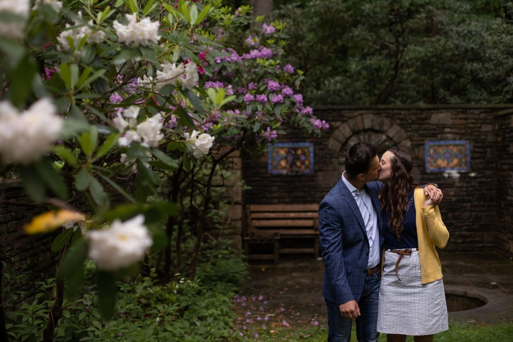 A romantic moment captured in a blooming garden with white flowers and stone architecture.