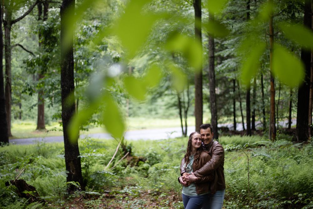 A couple embracing in a lush green forest setting during summer.