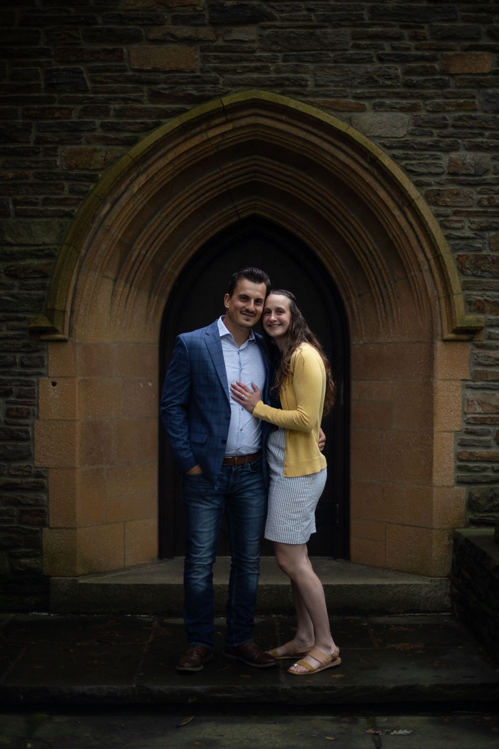 Couple posing in Gothic church doorway during engagement photo session.