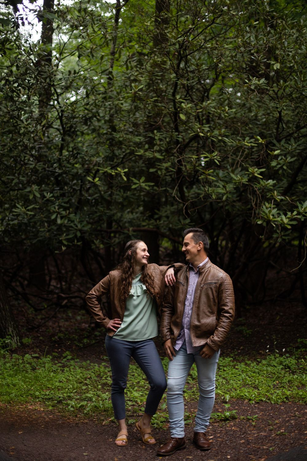 Couple sharing a lighthearted moment while standing on a wooded trail.