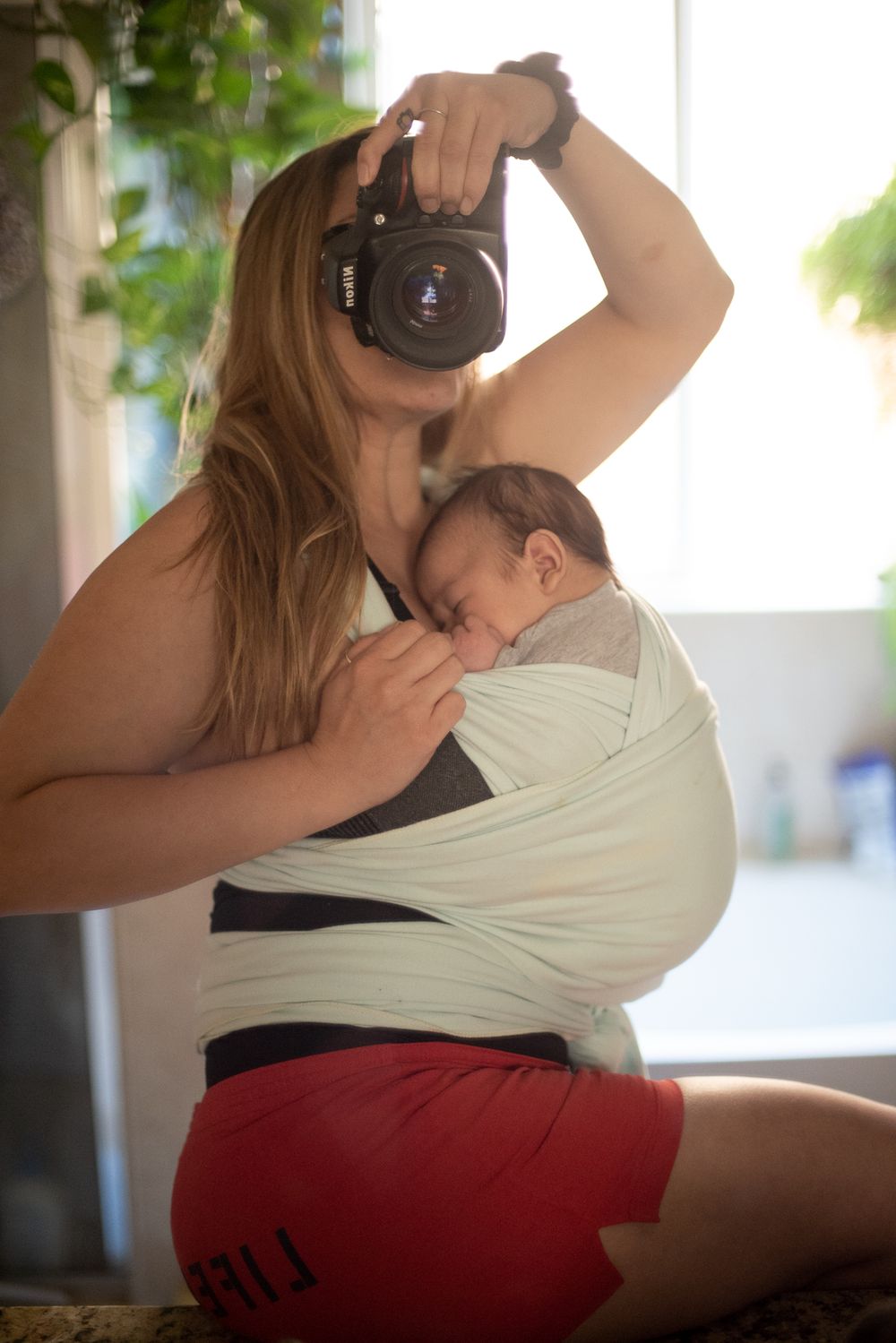 Person holding professional camera while wearing white wrap and red shorts.