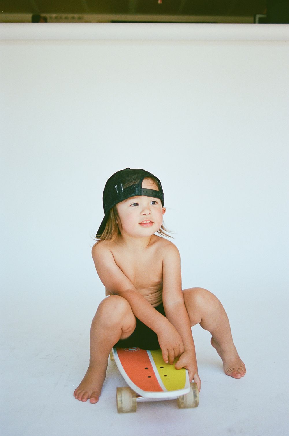 Baby wearing a baseball cap crawling on white background in sequence.