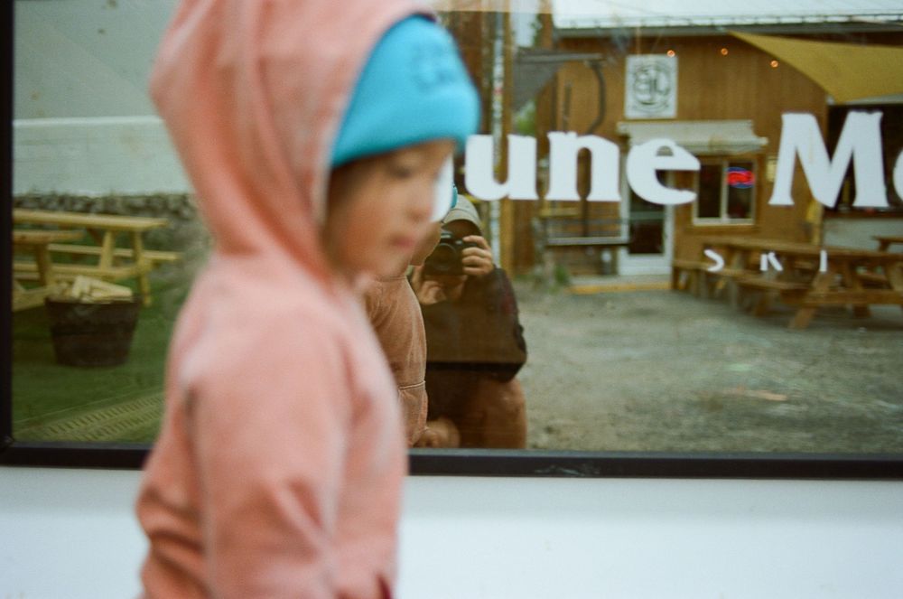 Person in pink clothing against blurred rustic building backdrop.