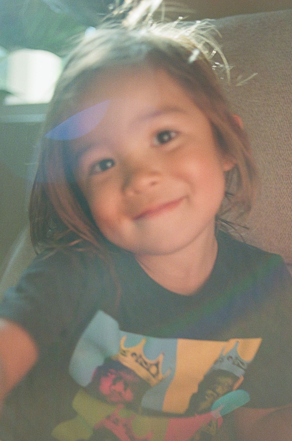 Child wearing graphic t-shirt poses for playful close-up photos.