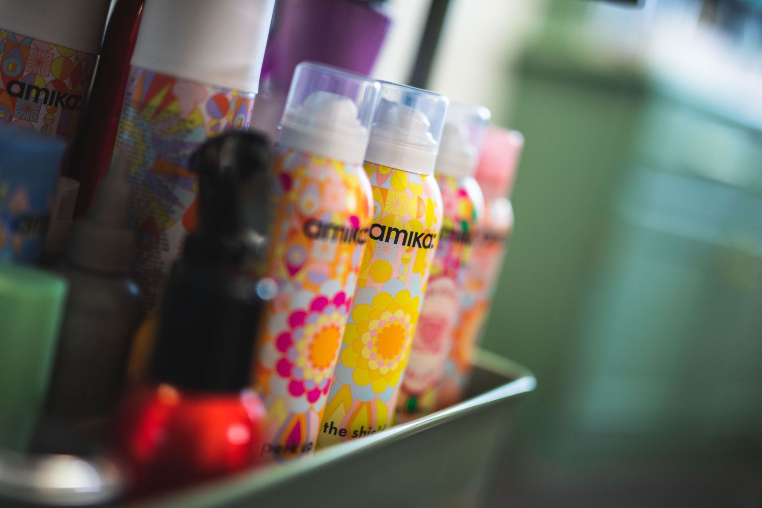 Colorful Amika hair product bottles displayed on shelf with soft focus background.
