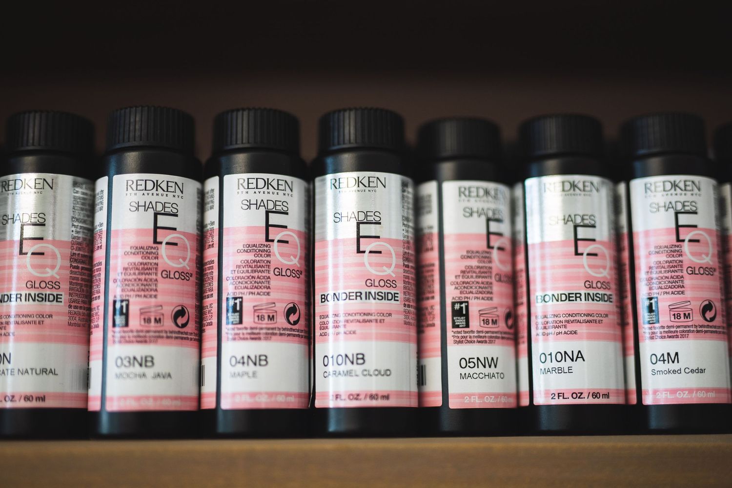 Close-up view of pink labeled hair color bottles arranged in a row.