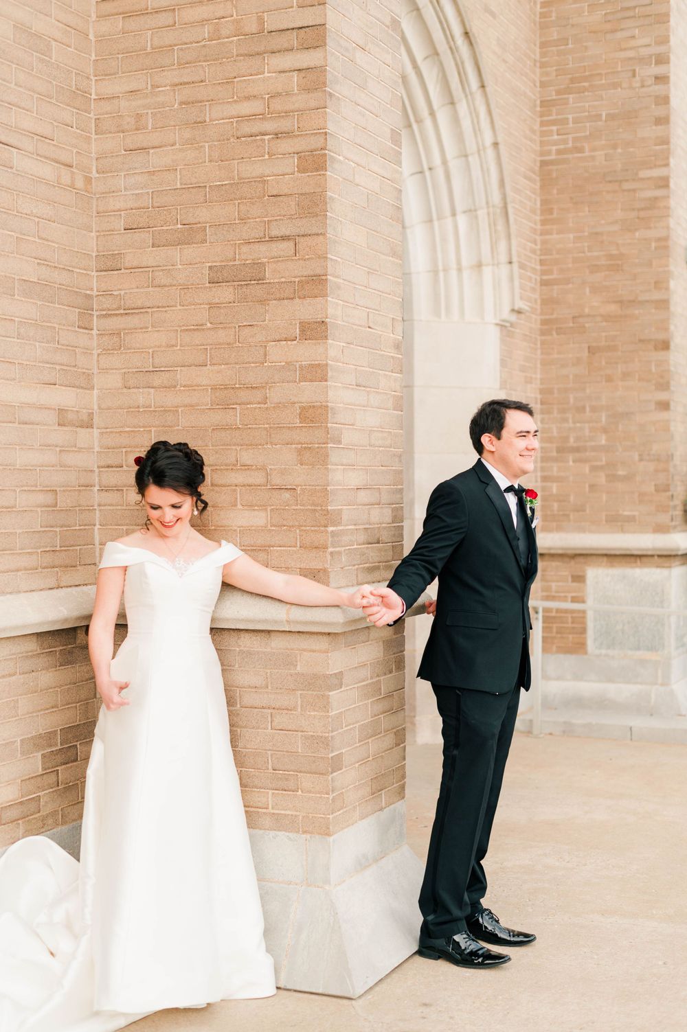 Bride and groom during their first touch on the steps at Holy Family Cathedral, Tulsa, OK before their wedding.