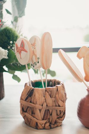 Woodland themed baby shower decorations with fox and deer cutouts in a rustic wooden vase.