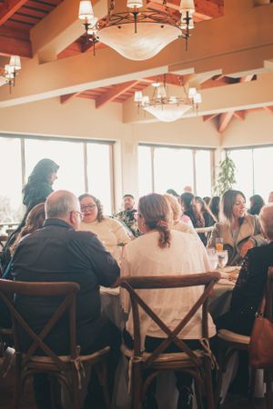 Guests gathered at round tables in an elegant venue with vaulted ceilings and chandeliers.