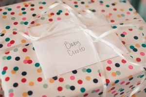 A polka dot wrapped present with a white bow and tag that reads 'Baby David'.