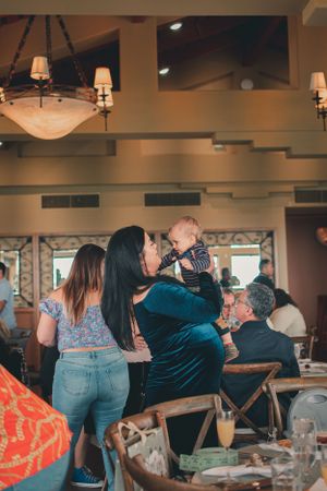 People gathered at an indoor celebration with chandeliers and decorative lighting.