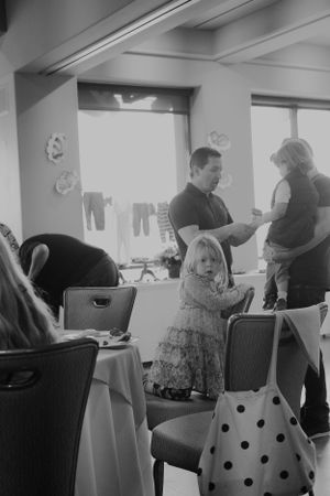 A black and white photo of people gathering at tables during a social event.
